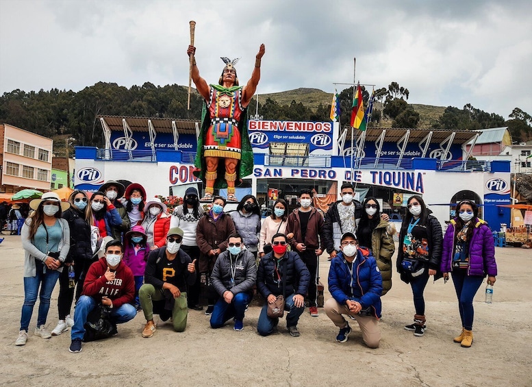 Un gruppo di persone che posa di fronte a un cartello con la scritta 'BIENVENIDOS SAN PEDRO DE TIQUINA'. 3