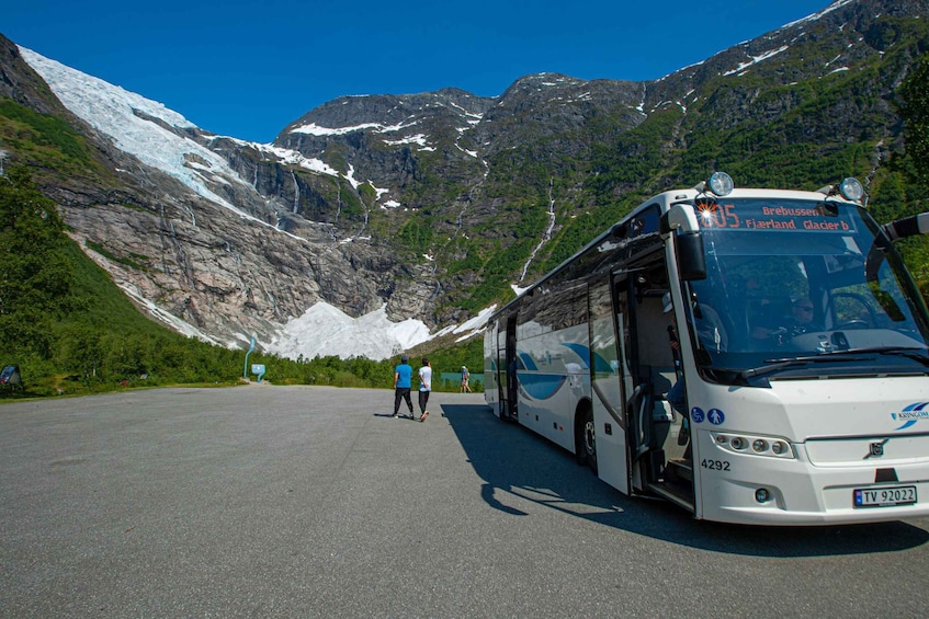 A bus at a mountain station with a glacier in the background. 2