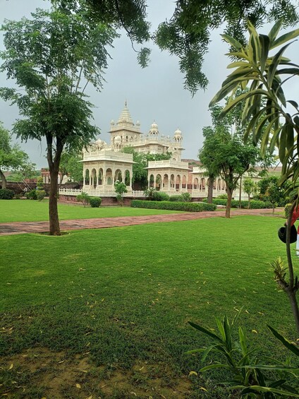 A large, ornate building with domes and arches, surrounded by lush green grass and trees. 4