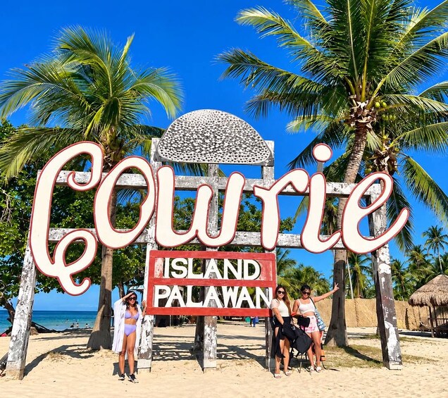 Schild am Strand für Coltrie Island Palawan, mit Palmen und dem Ozean im Hintergrund. 5