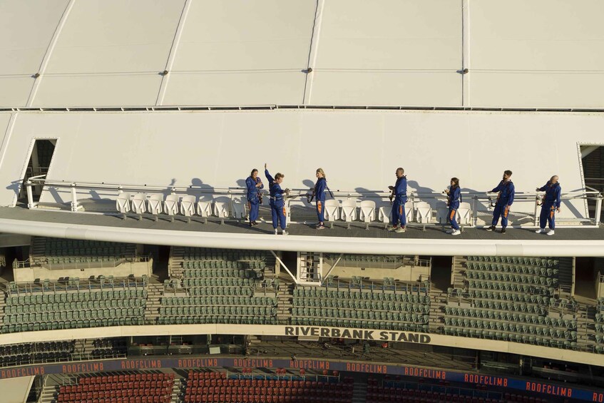 A stadium with multiple levels of seating and a group of people in blue uniforms on the upper level. 3