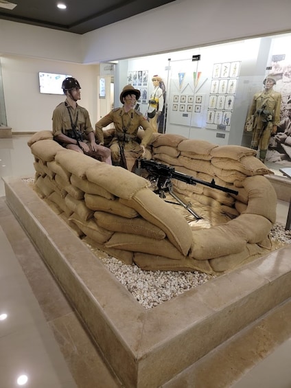 A museum exhibit with soldiers in uniform, a large sandbag display, and military artifacts. 3