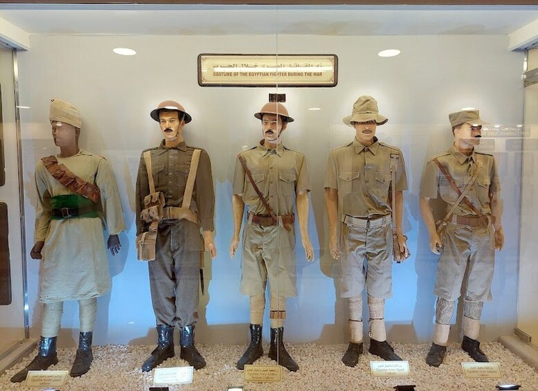 A display of Egyptian soldiers in uniform, including a figure with a green sash and another with a red sash, standing on a gravel floor. 1