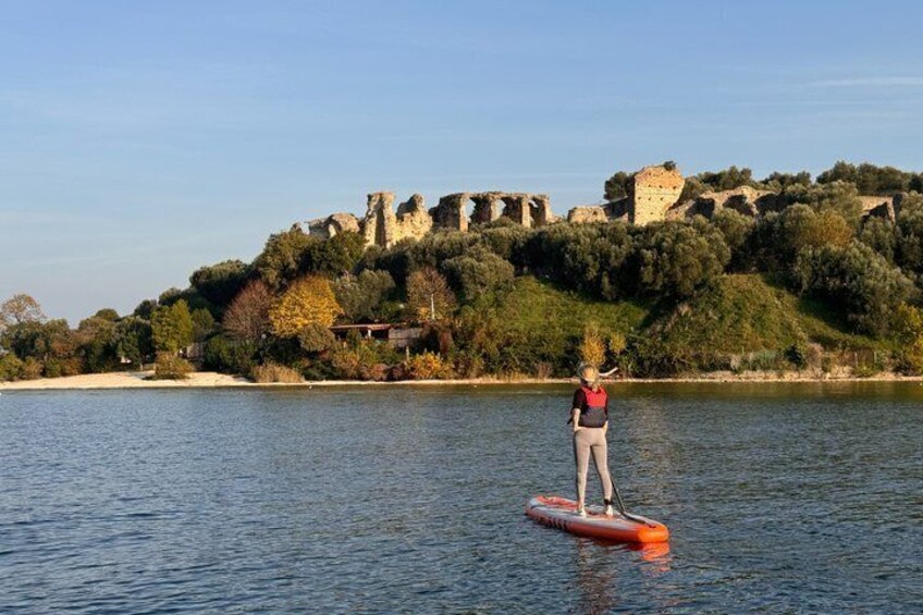 Una persona haciendo paddleboard en aguas tranquilas, con un castillo histórico al fondo. 4