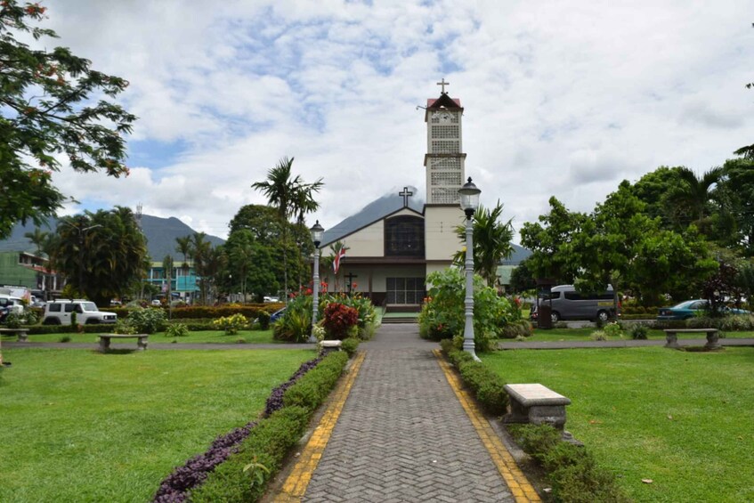 A church with a tall tower, surrounded by a well-maintained garden and a paved pathway leading to the entrance. 5