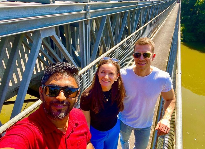 Drei Personen auf einer Metallbrücke über einem Fluss. 4