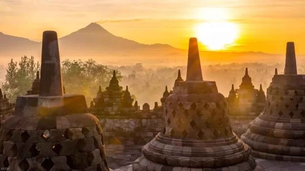 A row of ancient stone stupas with the sun setting behind them. 5