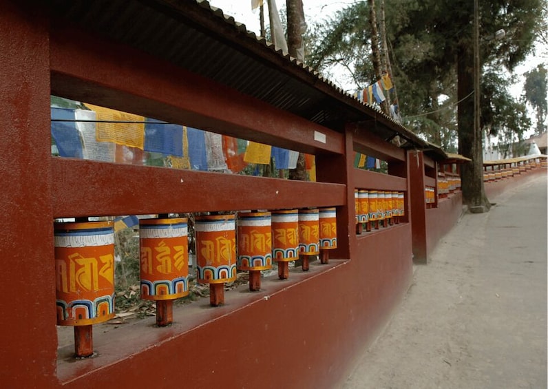 A red wall with prayer wheels and a clear sky. 2
