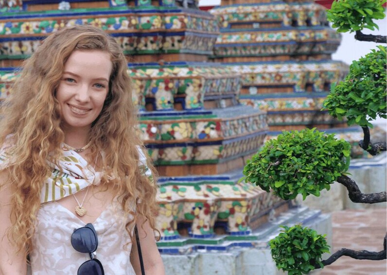 A person standing in front of a colorful, intricately designed building with multiple tiers. 3