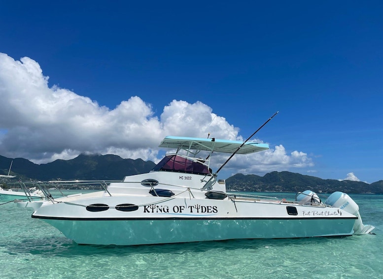 A boat named 'King of Tides' with a Yamaha outboard motor, anchored in clear turquoise water with mountains in the background. 3