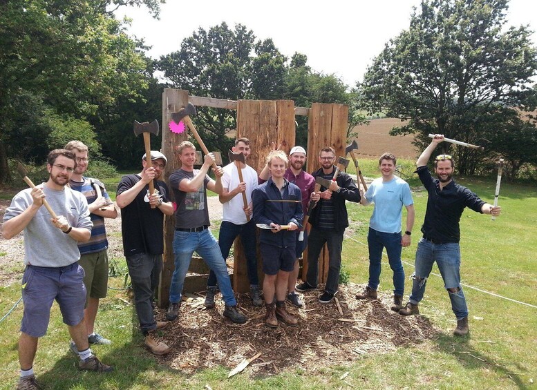A group of people holding axes in a wooded area. 5