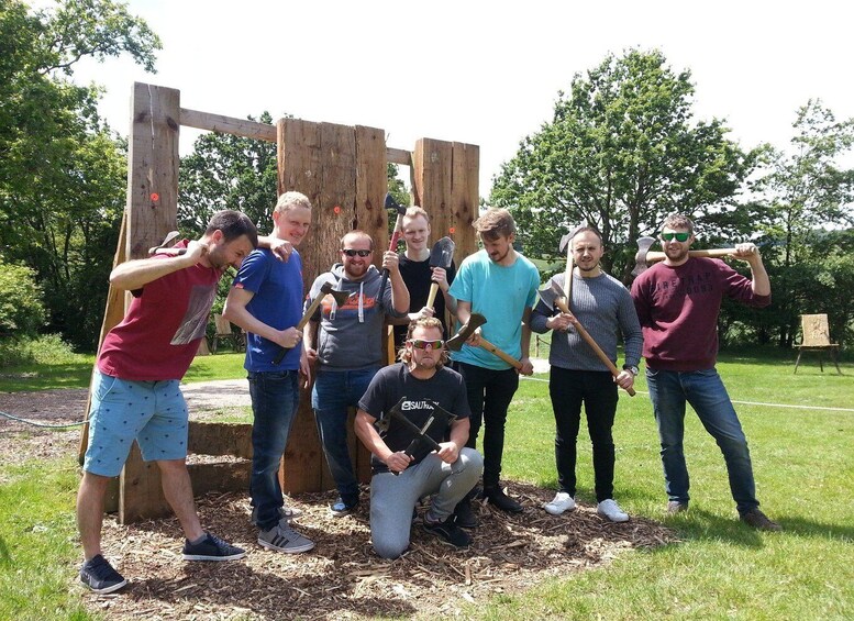 A group of people holding shovels and standing in front of a wooden structure in a park. 4
