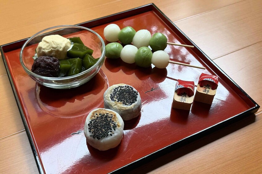 A tray with various Asian desserts, including mochi, green jelly, and skewered items. 3
