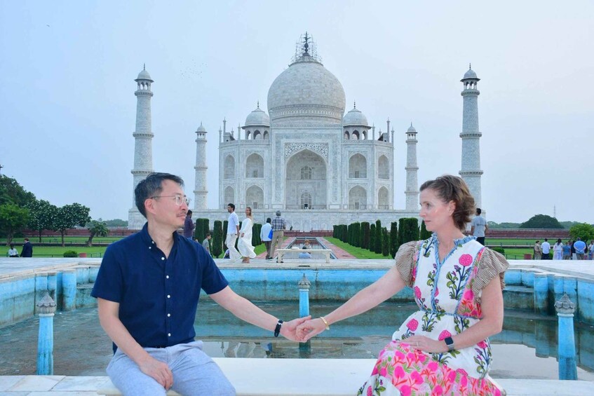 Two people holding hands in front of the Taj Mahal. 2