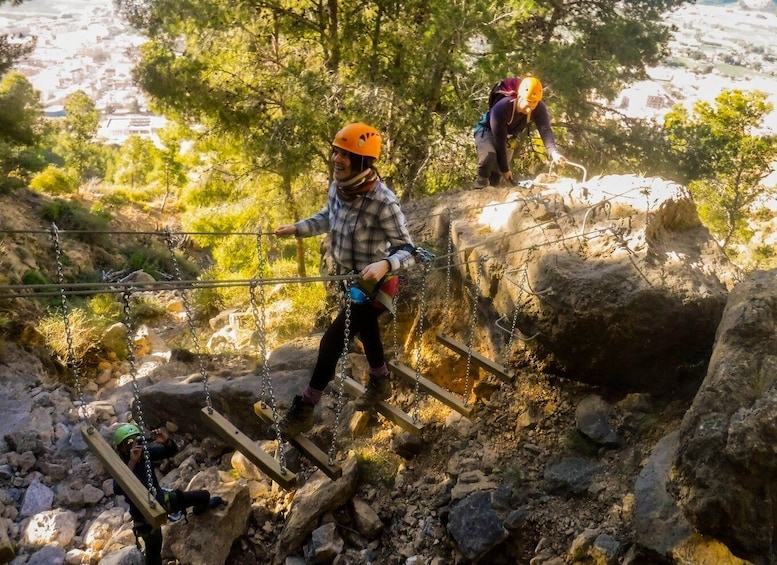 A person climbing a rocky terrain with chains and wooden planks. 1