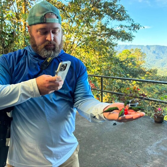 A person holding a smartphone with a scenic view of a mountainous landscape in the background. 1