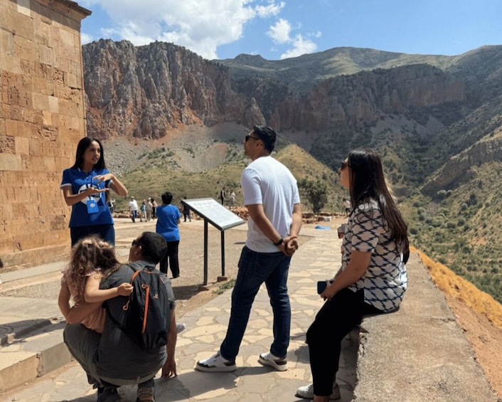 A group of people at a historical site with a stone wall and a view of a canyon. 2