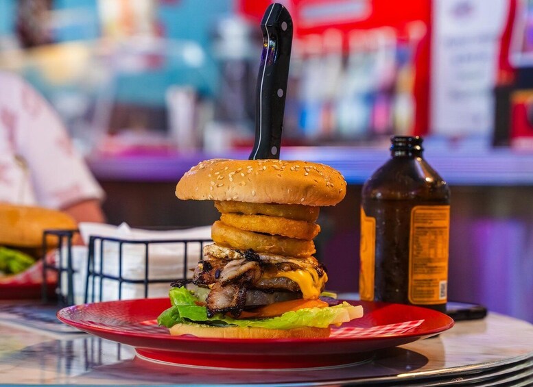 A large burger with a knife inserted into it, placed on a red plate. 5