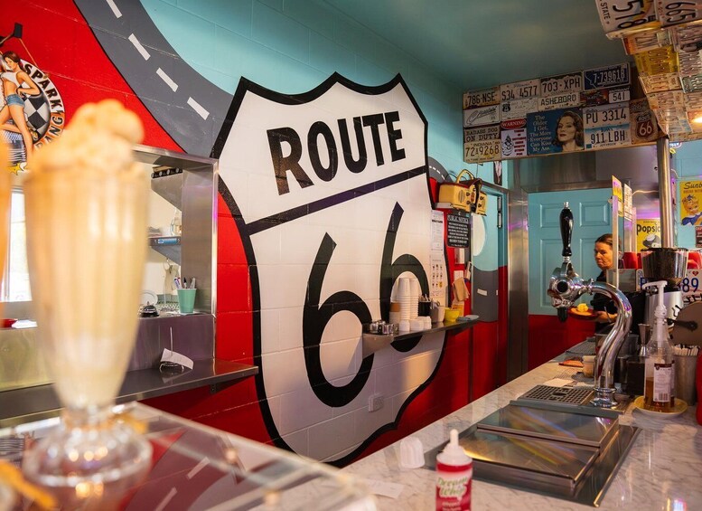 A Route 66-themed bar with a large shield sign, a milkshake, and vintage license plates. 4