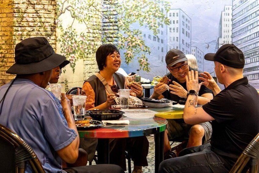A group of people dining at an outdoor table with a cityscape backdrop. 2
