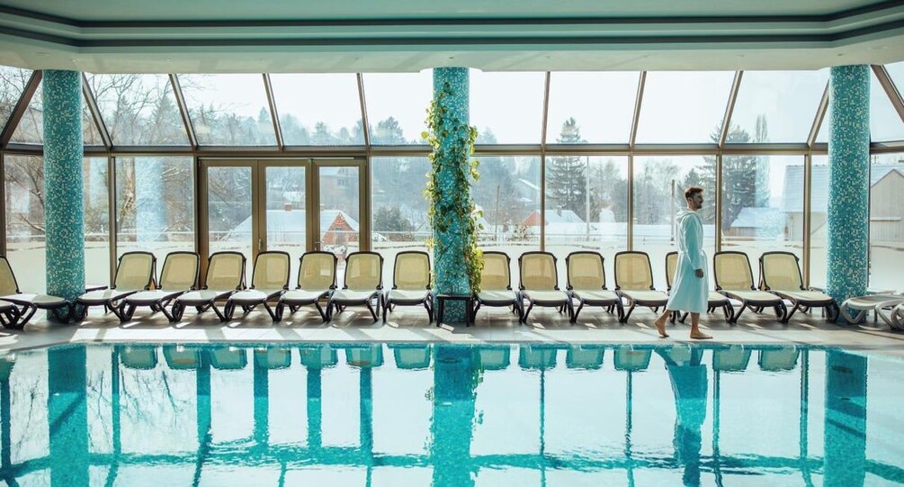 An indoor swimming pool with chairs and a person walking. 5