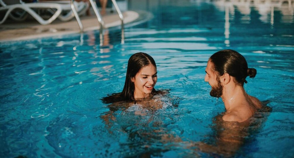 Two people in a swimming pool with clear blue water. 3