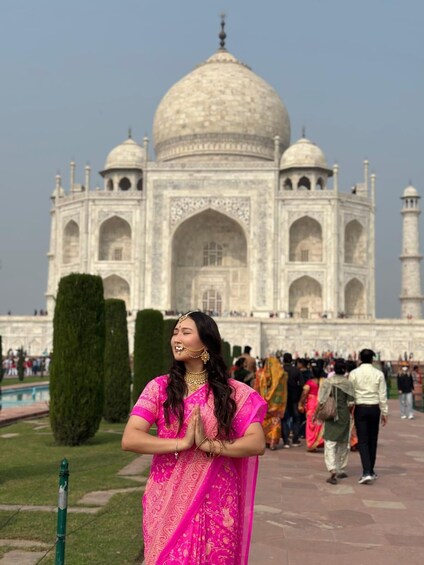 A person in a pink saree with a Mughal architectural landmark in the background. 5