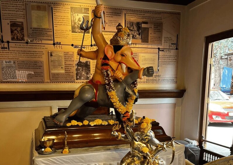 A statue of a deity with multiple arms, a trident, and a garland of marigold flowers. 5