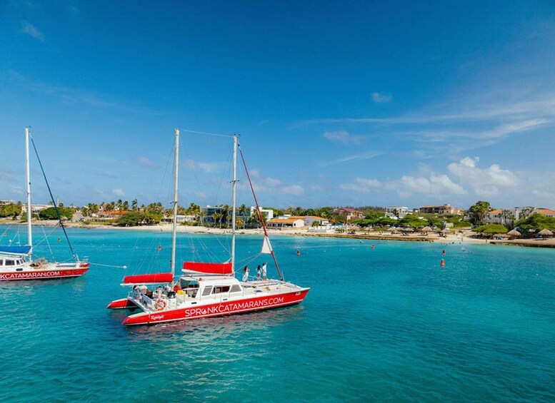 Three red and white boats on turquoise water with a beach and buildings in the background. 2