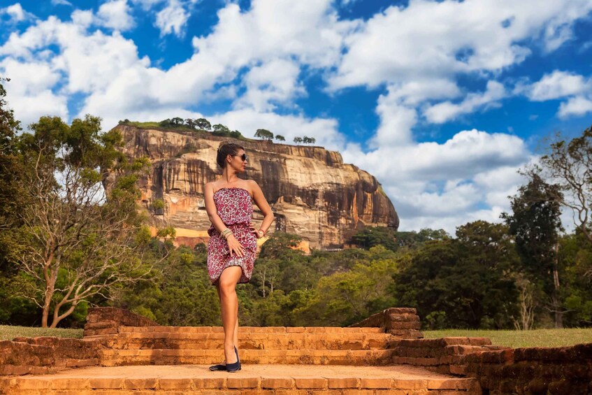 A person standing on stone steps with a large rock formation in the background. 4