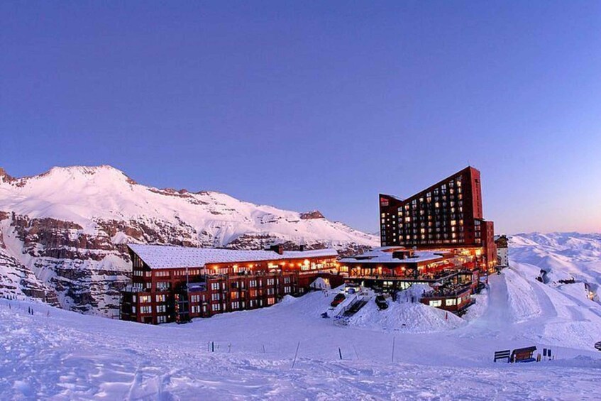 A snow-covered mountain resort with a distinctive building featuring a red facade and multiple windows. 3
