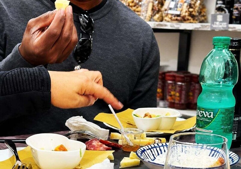 A person eating with a fork, a green bottle, and various dishes on a table. 3