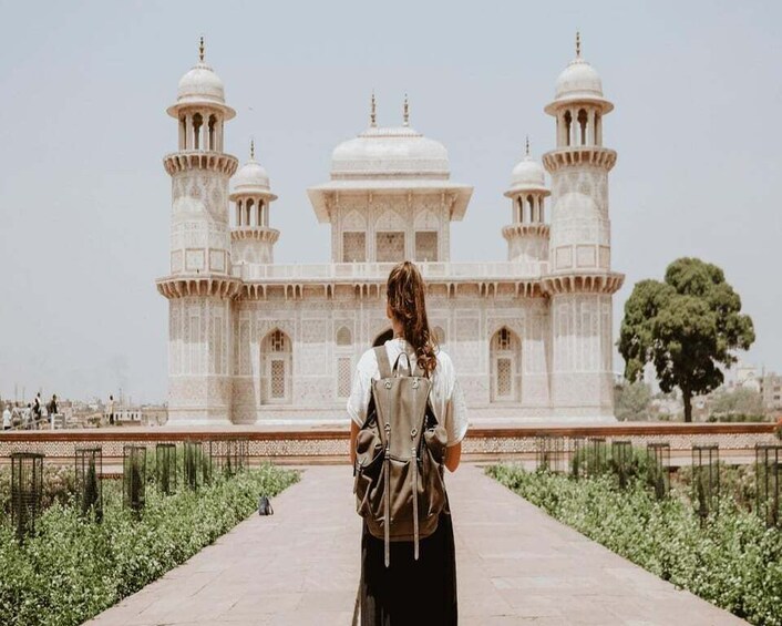 A person walking towards a large white building with domes and minarets. 5