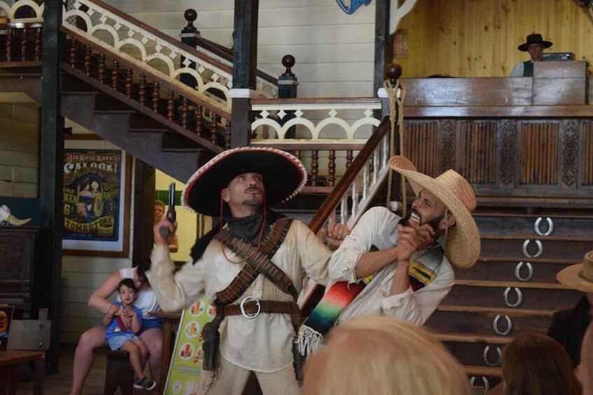 Una persona con sombrero de vaquero y disfraz, otra persona con sombrero de vaquero, y una escalera con barandillas decorativas. 2