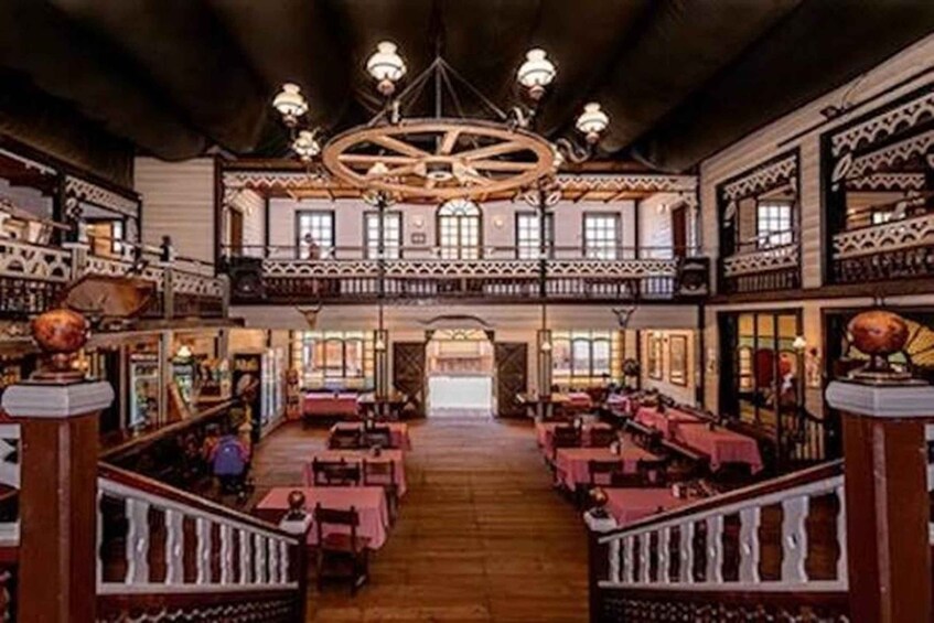 Una posada tradicional con pisos de madera, varias mesas de comedor y un candelabro central. 4