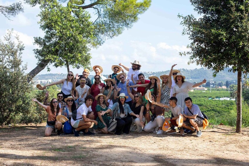 Un groupe de personnes posant à l’extérieur, avec des arbres et un paysage lointain en arrière-plan. 2