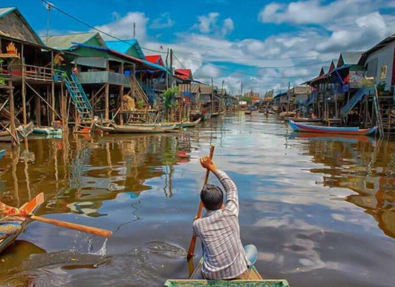A person paddling a boat in a waterway lined with traditional stilt houses. 2