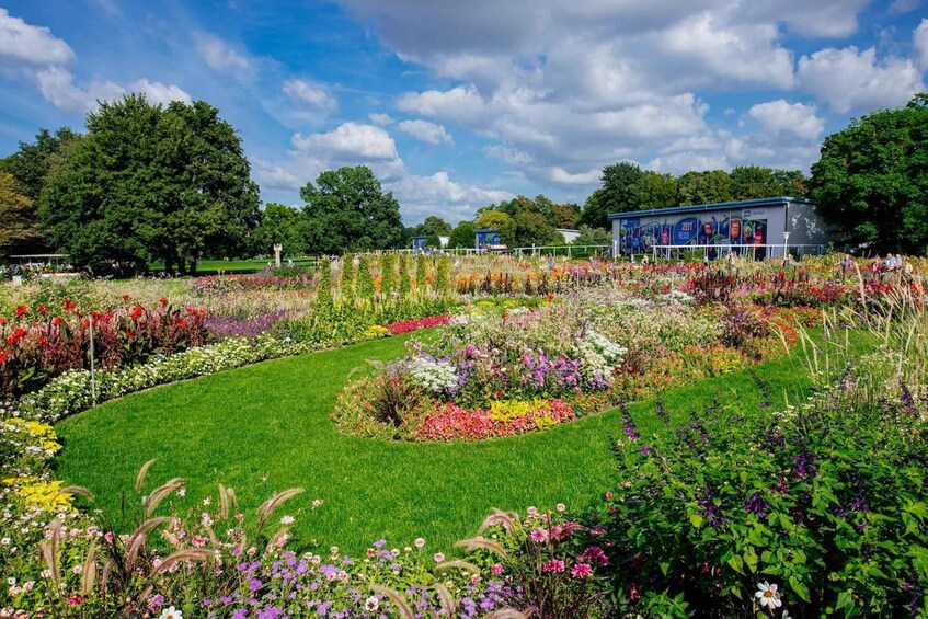 A vibrant flower garden with various colorful flowers and a building in the background. 1