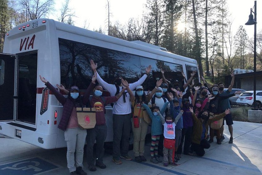 A group of people standing in front of a bus with their hands raised. 1
