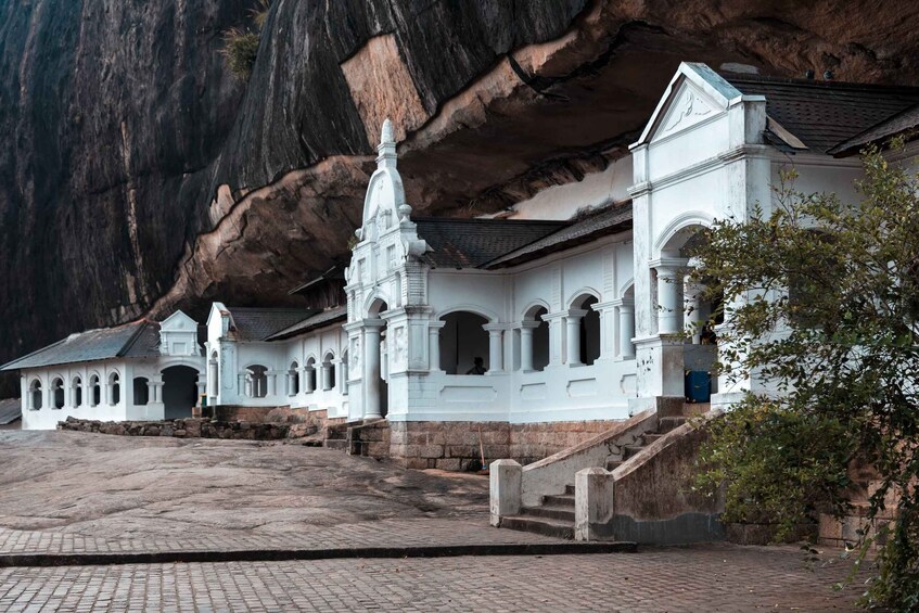 A white temple with a central spire, set against a rugged cliff backdrop. 5