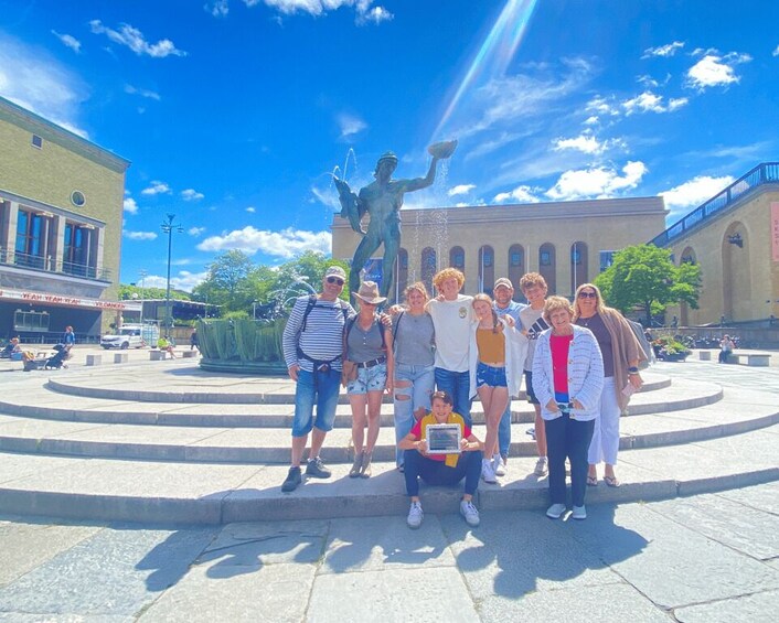 Un grupo de personas posando frente a una fuente con una estatua de una figura sosteniendo un cuenco. 5