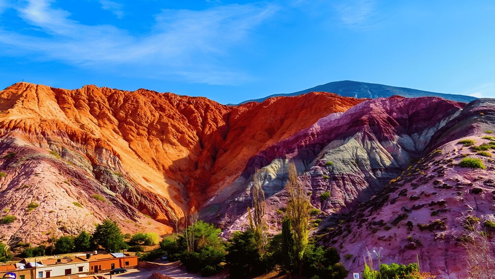 A mountainous landscape with a valley, a small settlement, and a mountain in the background. 3