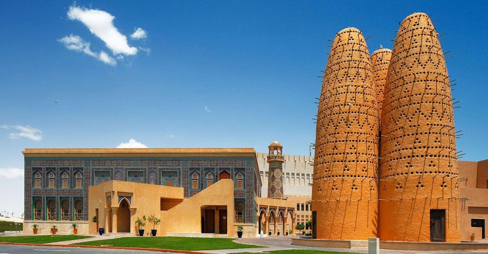 A historic building with intricate tile work and two tall, cylindrical towers with perforated surfaces. 2