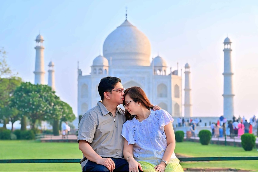 A couple sitting in front of the Taj Mahal with the monument in the background. 1