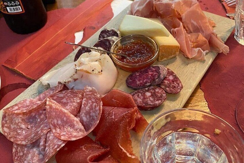 A charcuterie board with various meats, cheeses, and a small bowl of jam. 2
