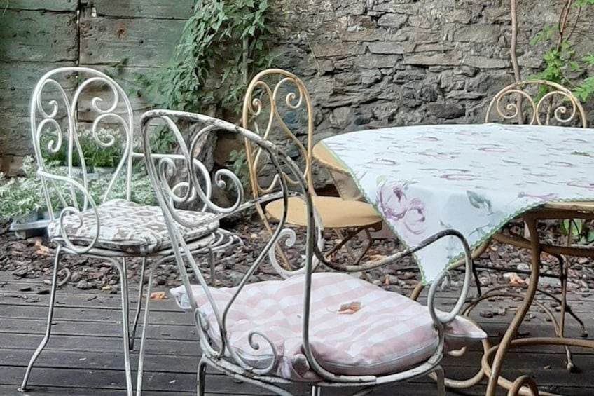 Outdoor metal chairs and a table with a floral tablecloth. 5