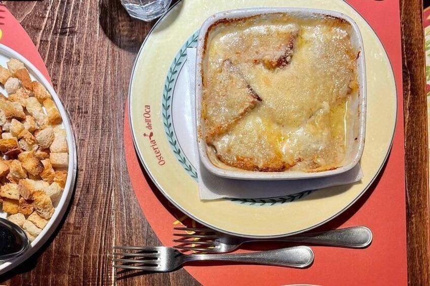 A dish of gratin on a plate with a fork and spoon beside it. 3