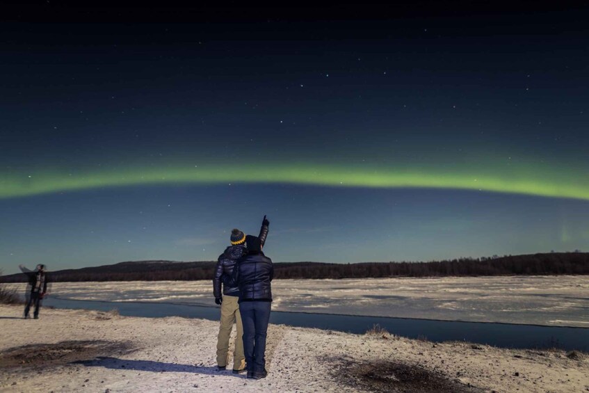 Two people observing the Northern Lights over a frozen landscape. 5