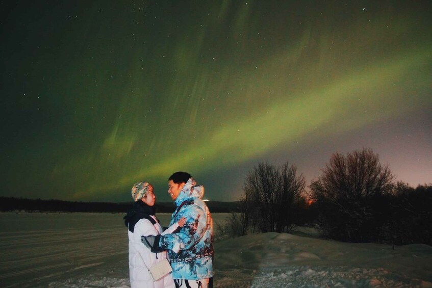 Two people embracing under a night sky with the aurora borealis. 3