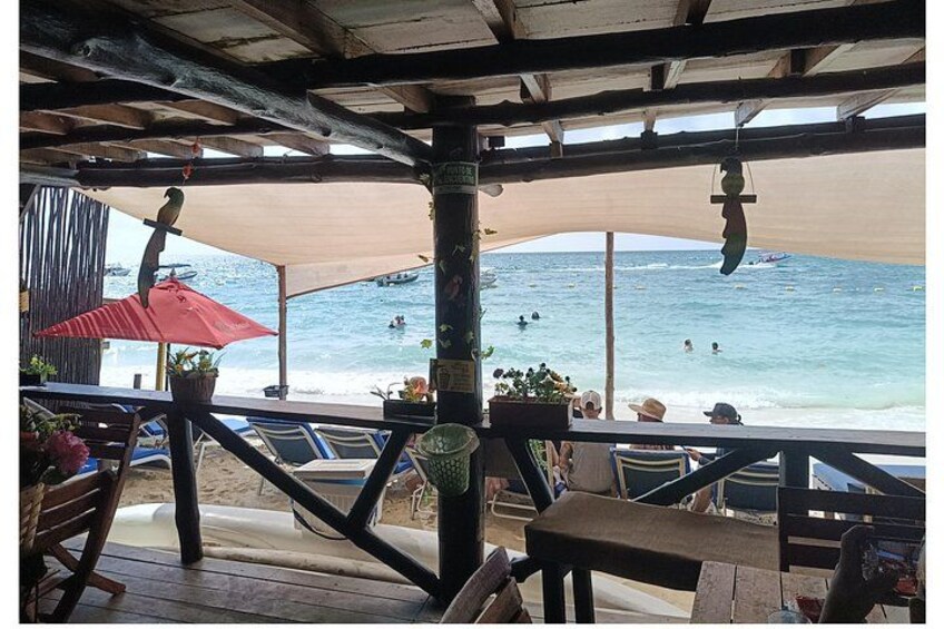 A beachside café with a view of the ocean, outdoor seating, and umbrellas. 3